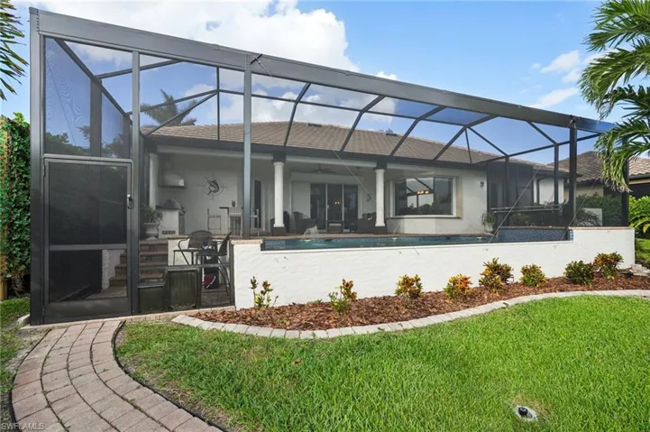 Back of property with a lawn, a patio area, glass enclosure, and ceiling fan