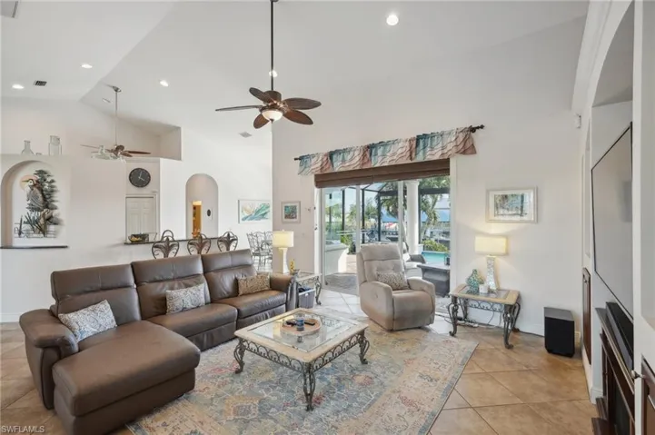 Tiled living room featuring ceiling fan and high vaulted ceiling