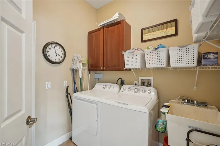 Laundry area featuring sink, washing machine and dryer, and cabinets