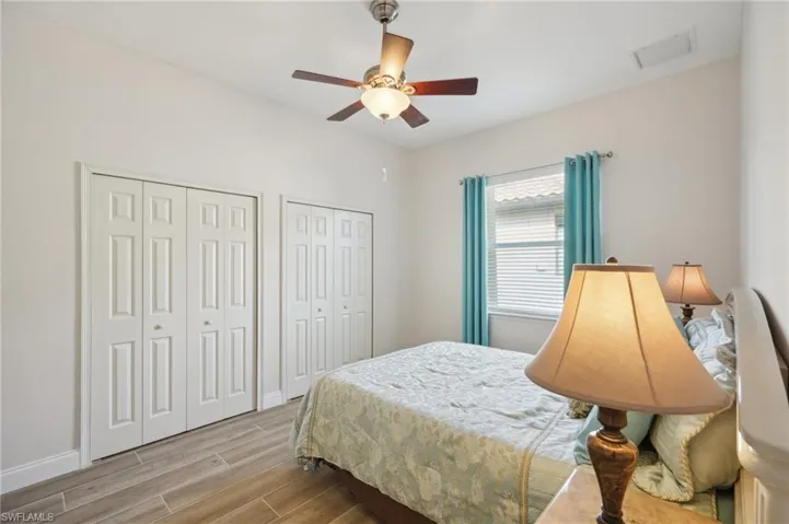 Bedroom with light hardwood / wood-style flooring, two closets, and ceiling fan
