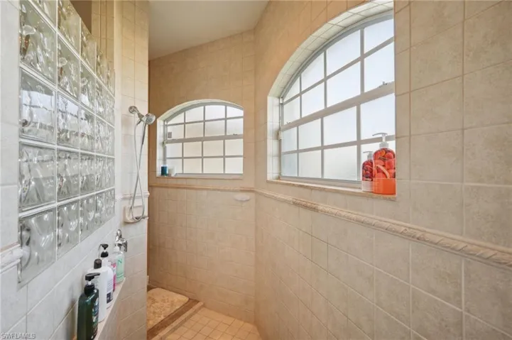 Bathroom with a healthy amount of sunlight, tile walls, and tiled shower