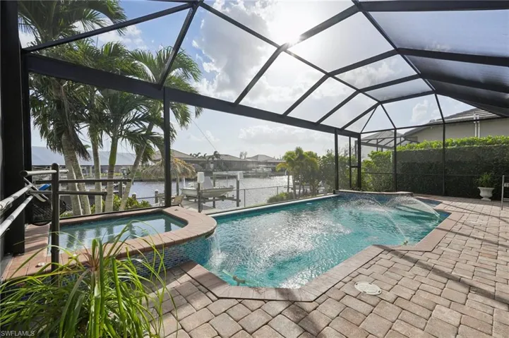 View of pool with a water view, a patio area, pool water feature, and glass enclosure
