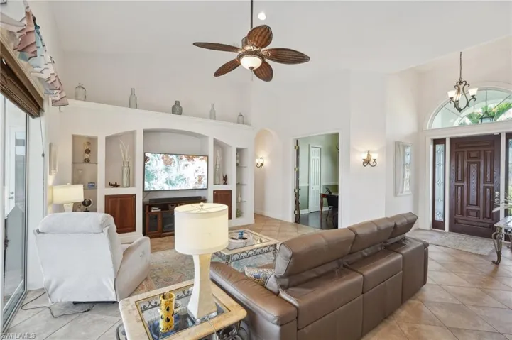 Living room featuring light tile patterned floors, built in features, and a high ceiling