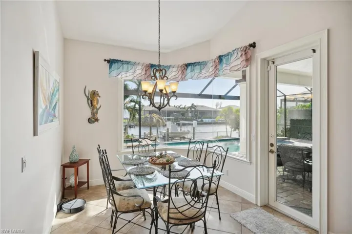 Dining room featuring a notable chandelier, a water view, and light tile patterned floors
