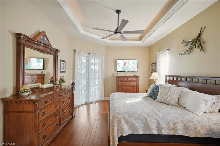 Bedroom featuring ceiling fan, a raised ceiling, crown molding, and dark hardwood / wood-style floors