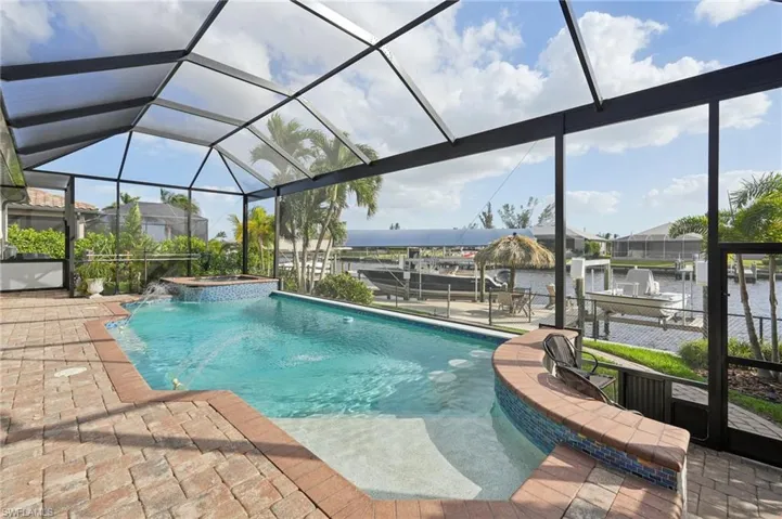 View of pool featuring pool water feature, an in ground hot tub, a water view, and glass enclosure