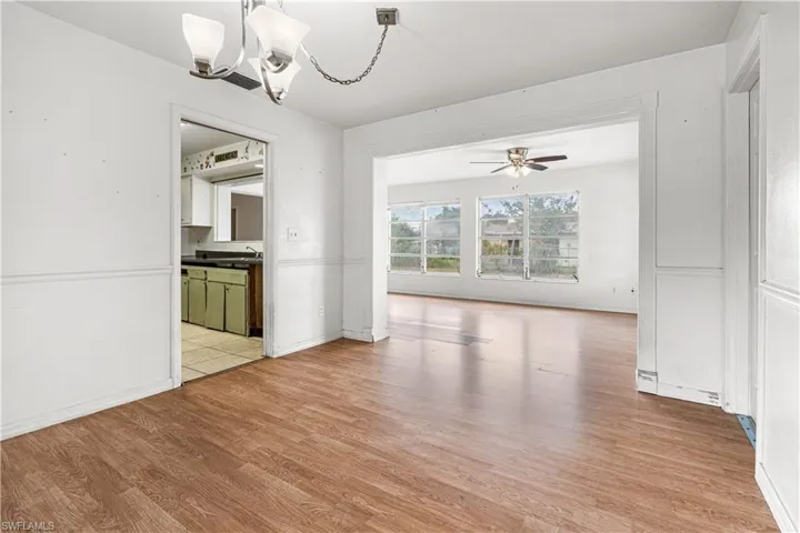 Unfurnished dining area with sink, light wood-type flooring, and ceiling fan with notable chandelier