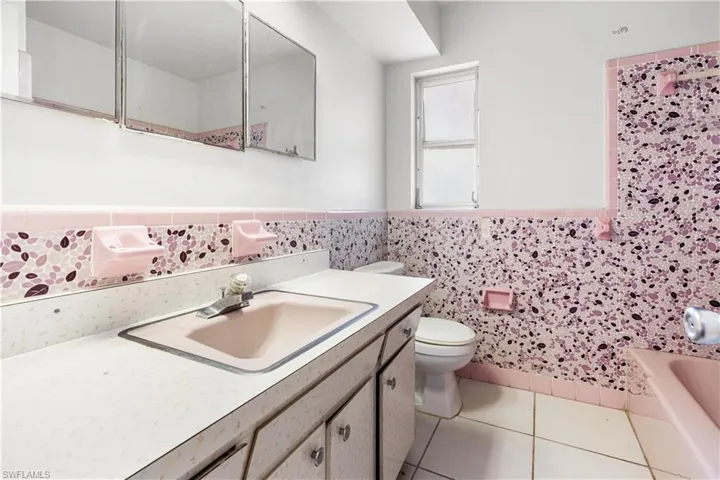 Bathroom with tile walls, oversized vanity, toilet, tile floors, and tasteful backsplash