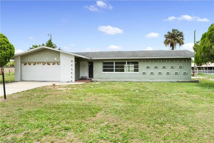 Single story home featuring a garage and a front lawn