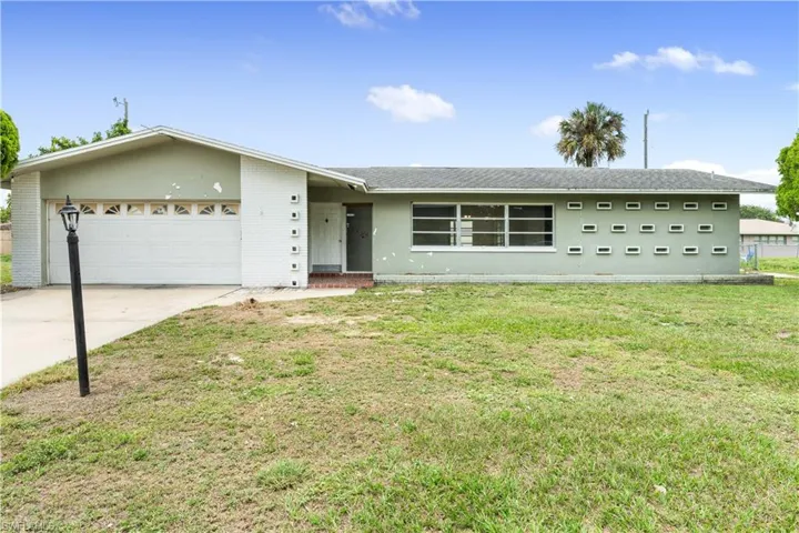 Ranch-style house featuring a front yard and a garage