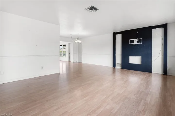 Unfurnished room with a notable chandelier and wood-type flooring