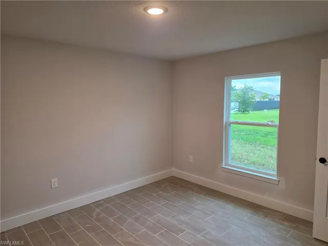 Room featuring neutral-toned walls, wood-finish tile flooring, recessed ceiling lighting, a single window, and white baseboards