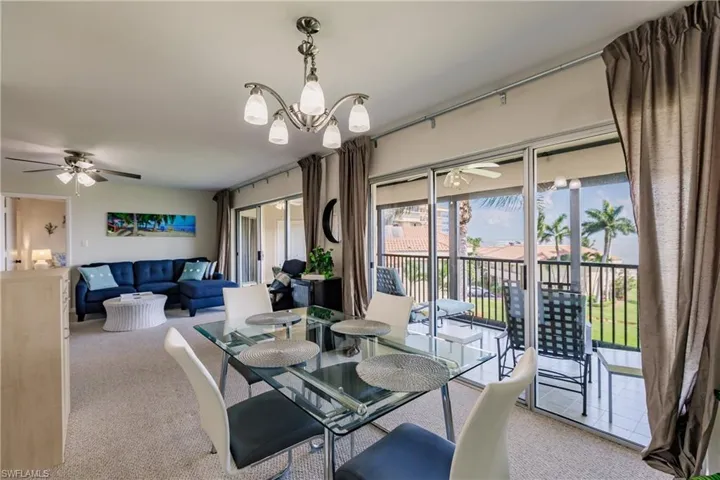 Carpeted dining room featuring ceiling fan with notable chandelier