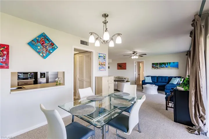 Dining room featuring carpet flooring and ceiling fan with notable chandelier