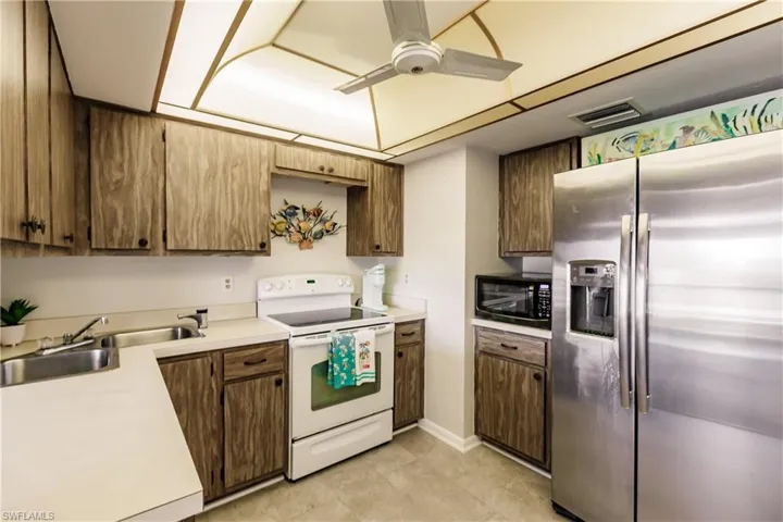 Kitchen with sink, electric range, stainless steel fridge with ice dispenser, ceiling fan, and light tile patterned flooring