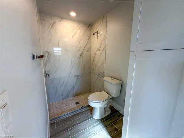 Bathroom with a marble finish shower and wood finish floors