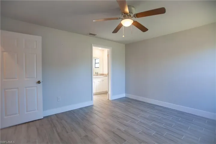Unfurnished bedroom featuring wood tiled floors, ceiling fan, and ensuite bath