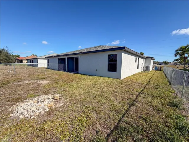 Back of property with a fenced backyard and stucco siding