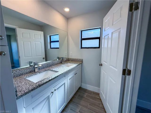 Full bath featuring double vanity and wood tiled floors