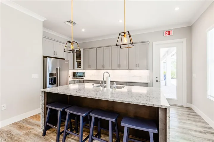 Community Kitchen featuring tasteful backsplash, sink, high quality fridge, a center island with sink, and light hardwood / wood-style floors