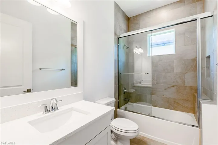 Full bathroom with vanity, tile patterned flooring, bath / shower combo with glass door, and toilet