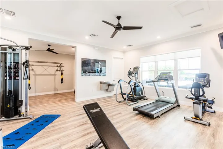 Workout area with ceiling fan and light hardwood / wood-style flooring
