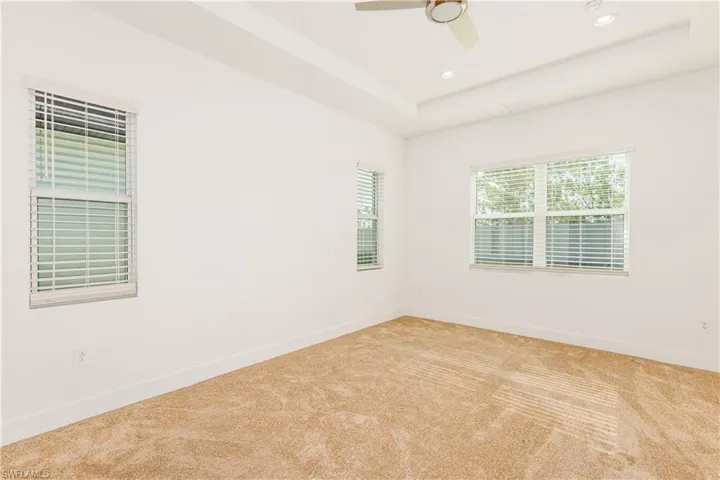 Primary room with a tray ceiling, ceiling fan, and light colored carpet