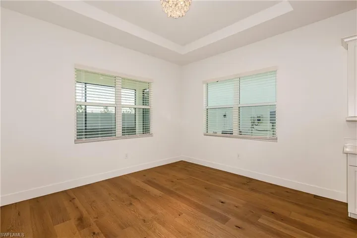 Dining room with an inviting chandelier, hardwood / wood-style flooring, and a raised ceiling