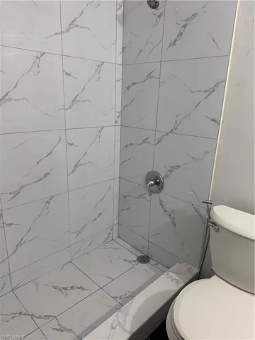 Bathroom with a marble finish shower and toilet