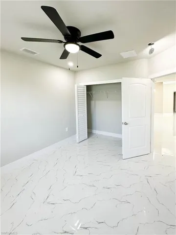 Unfurnished bedroom featuring a closet, light tile patterned floors, and ceiling fan