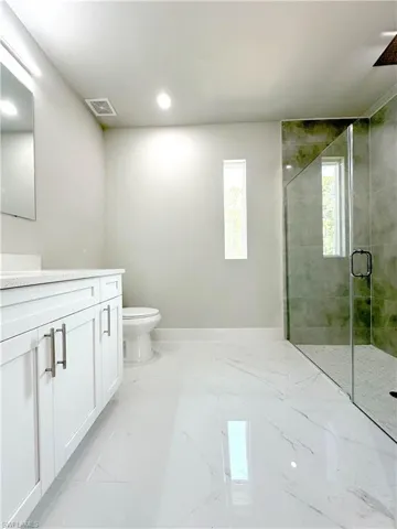 Bathroom featuring tile patterned floors, toilet, vanity, and an enclosed shower