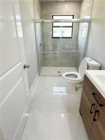 Bathroom featuring vanity, an enclosed shower, tile patterned flooring, and toilet