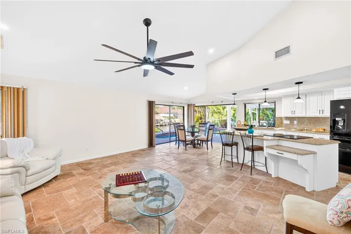 Living area with lofted ceiling, stone tile flooring, recessed lighting, and a ceiling fan