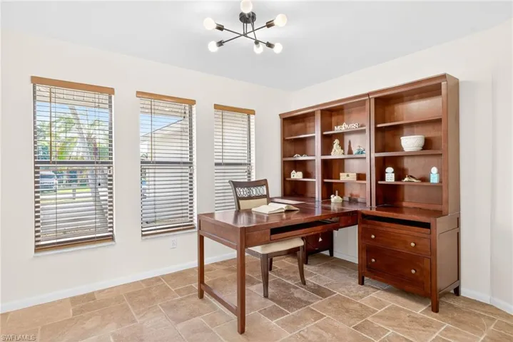 Office area or formal dining area with stone tile floors, a chandelier, and healthy amount of natural light
