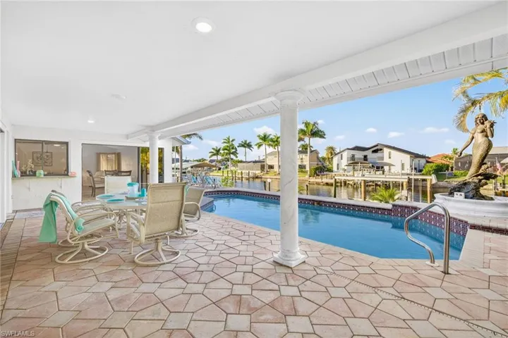 Looking out to the swimming pool from the master bedroom with a patio, a water view, outdoor dining area, and a residential view
