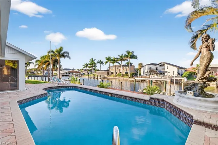 Outdoor pool with a water view, a patio area, and a residential view