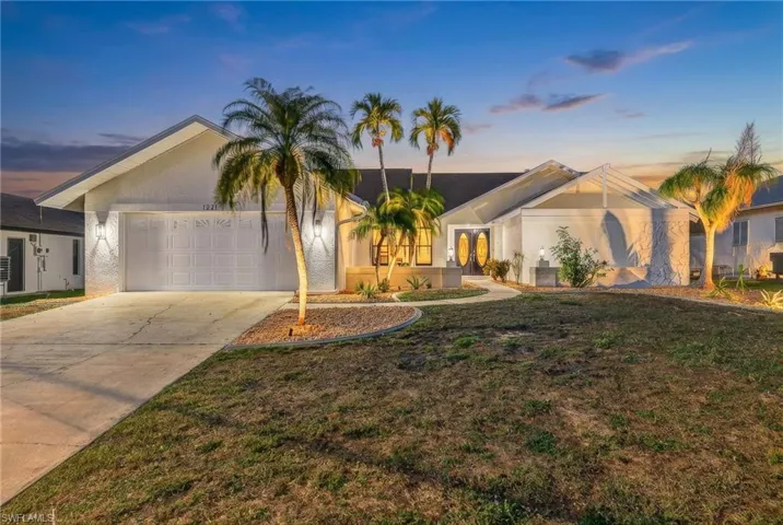 View of front of house featuring concrete driveway, stucco siding, a front yard, and a garage