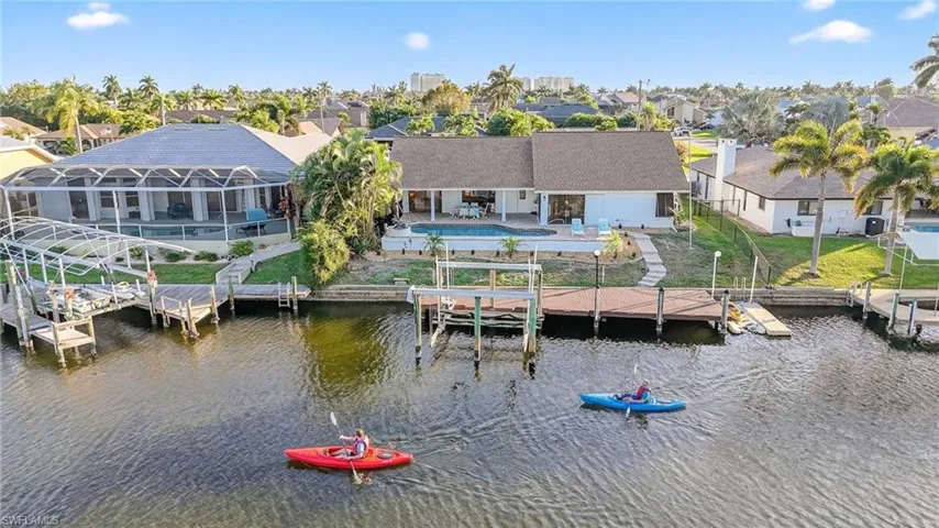 Dock area featuring a patio area, an outdoor pool, boat lift, a water view, and a residential view