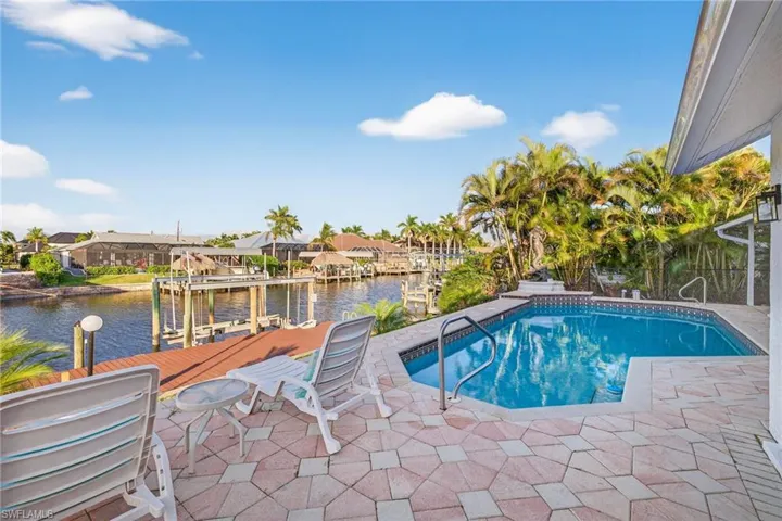 Outdoor pool featuring a water view, boat lift, a dock, a patio area, and a residential view