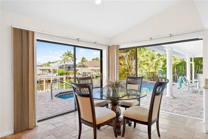 Dining area featuring lofted ceiling, a water view, stone tile flooring, and recessed lighting