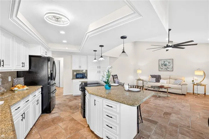 Kitchen featuring white cabinetry, light stone countertops, open floor plan, and recessed lighting