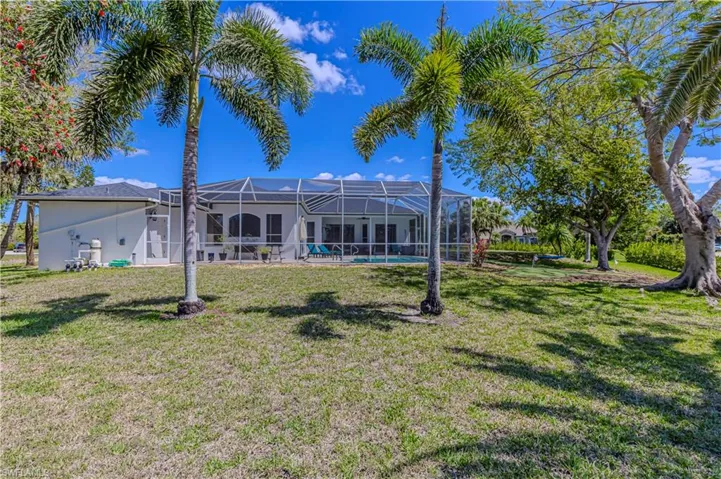 Rear view of property w/ outdoor pool, yard & screen enclosure