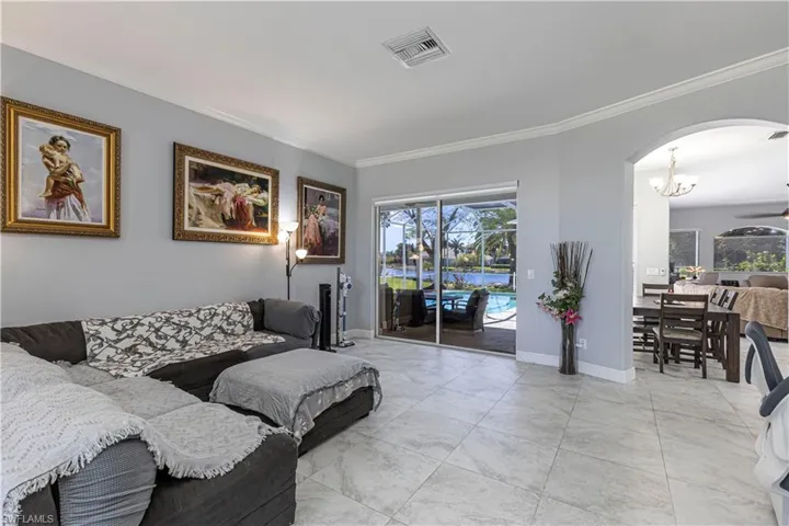 Living area with arched walkways, crown molding, plenty of natural light, and a chandelier