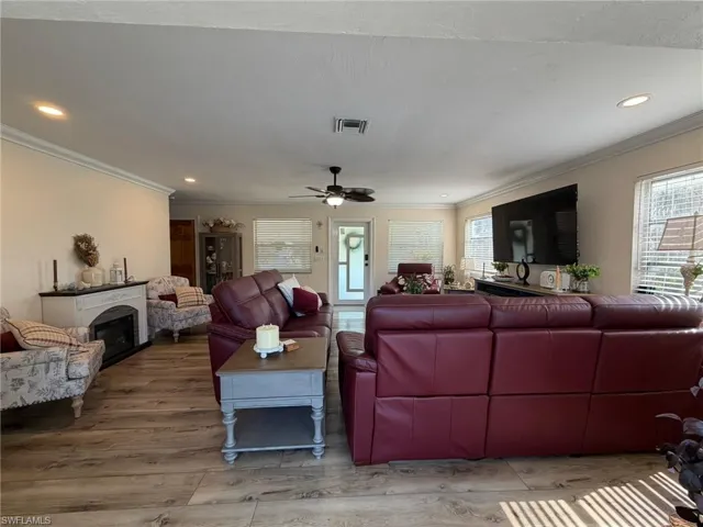 Living room featuring a fireplace, ornamental molding, recessed lighting, healthy amount of natural light, and wood finished floors