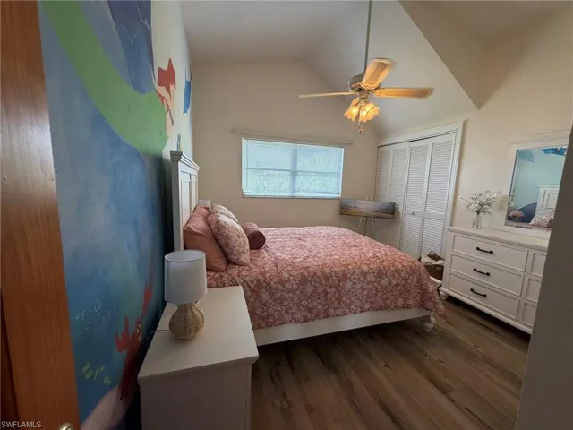 Bedroom with dark wood finished floors, ceiling fan, lofted ceiling, and a closet