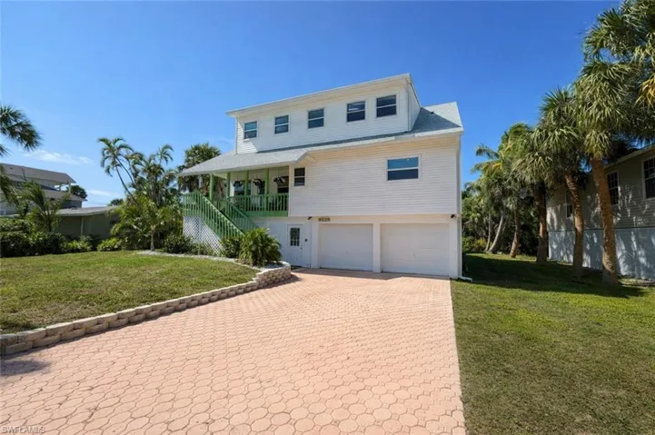 Coastal inspired home with a front yard, a garage, and decorative driveway