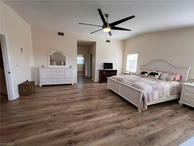 Bedroom with a ceiling fan, visible vents, and wood finished floors