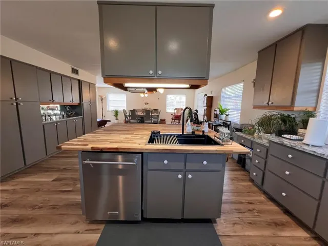 Kitchen with dark wood-style floors, gray cabinets, visible vents, a sink, and butcher block countertops