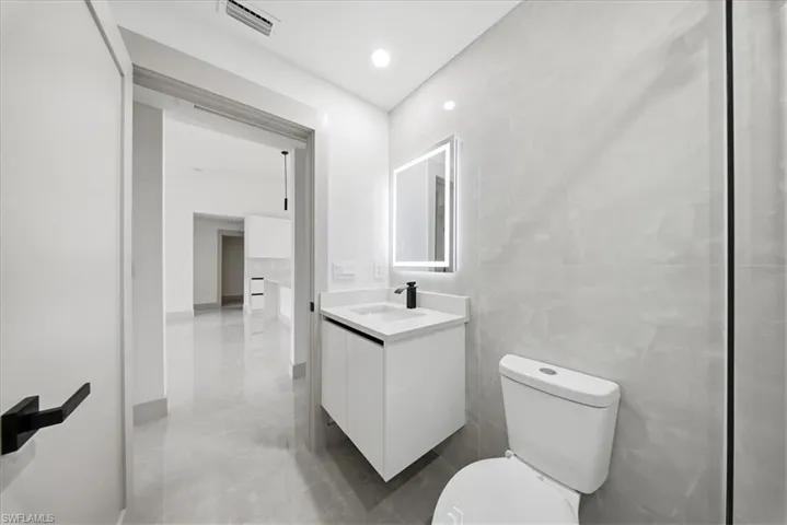 Half bathroom with vanity, tile walls, and recessed lighting