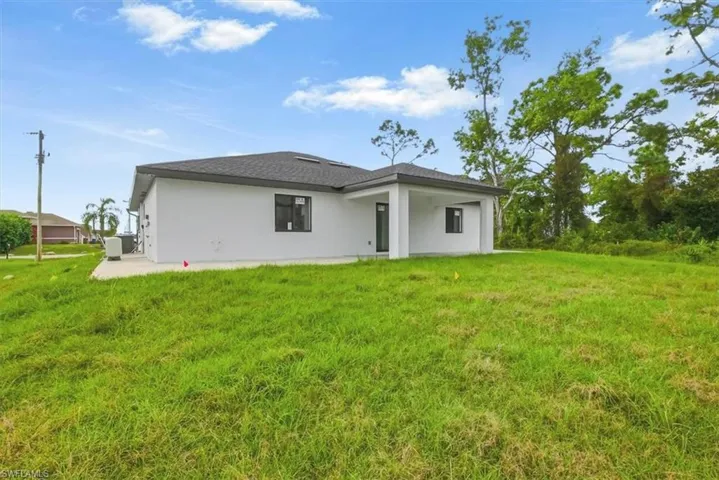 Back of house featuring a patio, a lawn, stucco siding, and a shingled roof